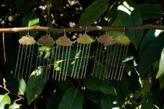 five gold hearts hanging from a tree branch with chains attached to them and dangling from the branches