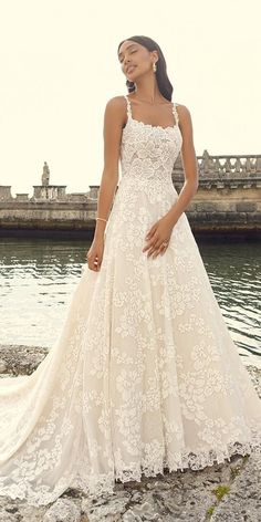 a woman in a wedding dress standing by the water