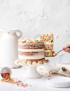 a person is cutting into a cake with sprinkles on the table next to it