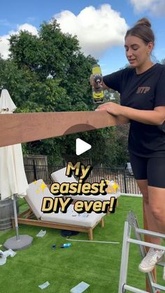 a woman in black shirt and shorts holding up a large wooden plank on top of grass