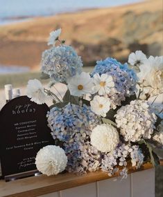 blue and white flowers in a vase on a window sill next to a plaque