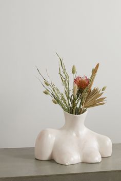 a white vase with flowers in it sitting on a table