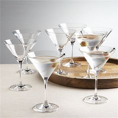 several martini glasses are lined up on a wooden platter and ready to be served