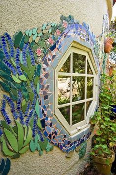 a window in the side of a building that has plants and flowers on it, next to a potted plant