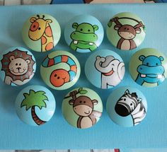 a bunch of buttons with animals on them sitting on a blue tablecloth next to each other