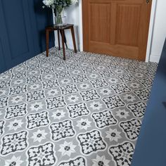 a blue and white tiled floor in a room with wooden door, side table and planter