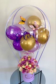 a vase filled with balloons and flowers on top of a table