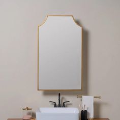 a bathroom sink sitting under a mirror next to a wooden counter top with two faucets