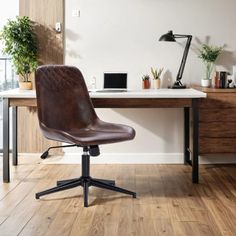 a brown leather office chair sitting on top of a wooden desk next to a window