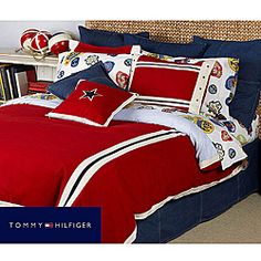 a bed with red and white comforters, pillows and pillow cases on top of it