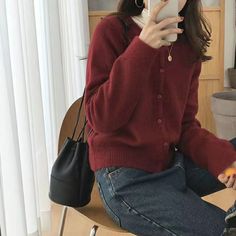 a woman sitting on top of a wooden chair holding a cell phone