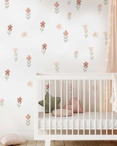 a baby's room with pink flowers on the wall and white crib bed