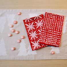 two red and white napkins sitting on top of a table next to candy canes