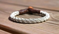 a white braided bracelet sitting on top of a wooden table