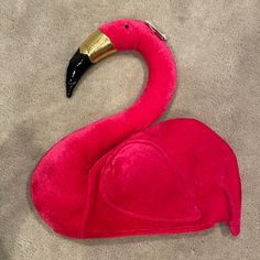 a pink flamingo stuffed animal laying on the floor next to a black and gold object