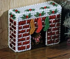 a knitted christmas decoration with stockings hanging from the roof and decorations on the windowsill