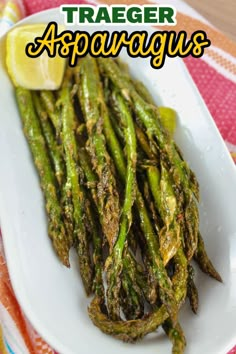 grilled asparagus on a white plate with lemon wedges