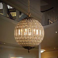 a chandelier hanging from the ceiling in a large room with stairs and windows