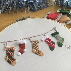 an embroidered christmas stocking hanging on a line next to other stockings and socks in the hoop