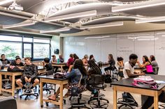 students are sitting at their desks in an open room with chalkboards on the walls