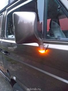 the side view mirror of a van with its lights on and it's door open