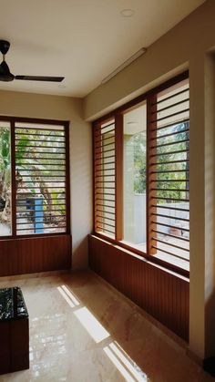 an empty room with large windows and wooden shutters