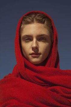 a woman wearing a red shawl and looking at the camera with a blue sky in the background