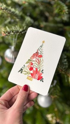 a person holding up a card with a christmas tree on it