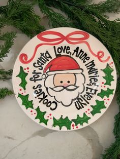 a ceramic plate with a santa clause on it's face and holly wreath around the edge