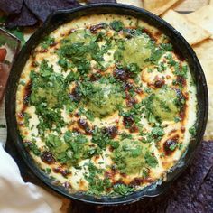 a black pan filled with food next to tortilla chips and guacamole