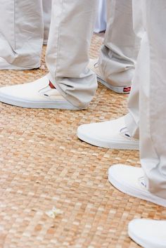 several people in white shoes standing on a woven floor with their legs crossed and feet tucked under them