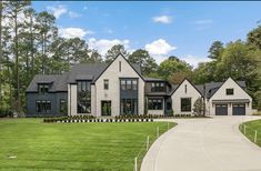 a large house with lots of windows in the front yard and driveway leading up to it