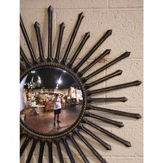 a mirror that is on the side of a wall with people walking in front of it