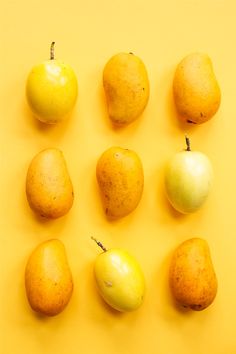 nine pears and two oranges on a yellow background