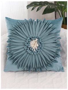 a blue pillow with a large flower on it's back and the center is made out of pleated fabric