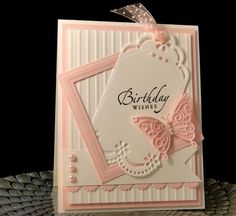 a pink and white birthday card with a butterfly on the front, sitting on top of a table