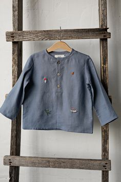 Forest long sleeve unisex shirt with three coconut buttons is made of 100% soft medium weight linen. The shirt is suitable for both girls and boys.  Details: - Choose size in the drop down menu - Colour: Dusty blue - Composition: 100% Oeko-Tex certified linen - Embroidered hedgehog, pine tree, autumn leaves, mushroom, berries, acorn - from both sides (front and back) - Three coconut buttons in the front - Medium weight linen - Unisex  - Relaxed silhouette - Linen care: machine wash gentle; tumbl Embroidered Long Sleeve Light Blue Blouse, Cotton Long Sleeve Tops With Buttons, Light Blue Long Sleeve Cotton Blouse, Blue Long Sleeve Shirt With Buttons, Light Blue Embroidered Cotton Shirt, Light Blue Cotton Embroidered Shirt, Casual Embroidered Long Sleeve Tops, Blue Cotton Shirt With Floral Embroidery, Blue Long Sleeve Tops With Buttons