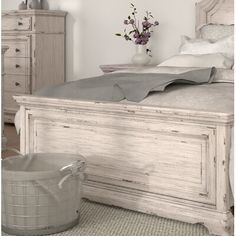 a white bed sitting in a bedroom next to a vase with flowers on top of it