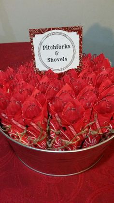 red roses are in a metal bowl with a sign that reads pitchforks & shovels