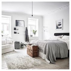 a bedroom with white walls and wooden flooring has a large bed, two couches, and a rug on the floor