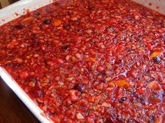 a white dish filled with red food on top of a wooden table