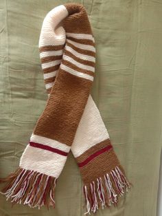 a brown and white scarf laying on top of a bed