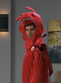 a man in a red costume with a shark on his head and arms, standing next to a couch