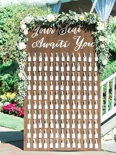 a wooden sign with flowers and greenery on it