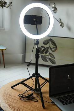 a laptop computer sitting on top of a wooden table in front of a camera light