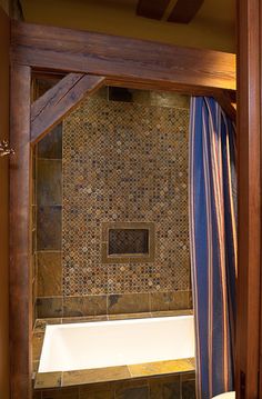 a bath tub sitting under a window next to a wooden framed door in a bathroom