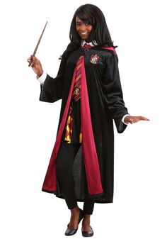 a woman in a harry potter costume holding a wand and pointing to the side with both hands