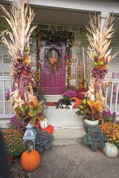 a front porch decorated for fall with pumpkins, corn stalks and other decorations on display