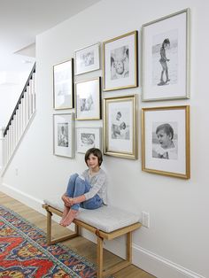 a woman is sitting on a bench in front of some framed pictures with the words how to display beautiful family photos in a gallery wall