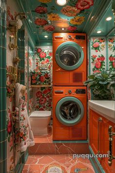 an orange washer and dryer in a bathroom with floral wallpaper on the walls